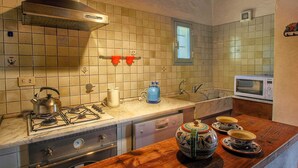 A kitchen with a gas stove, a microwave, and a wooden countertop. - Cozy Farmhouse with Swimming Pool in Le Tolfe near Florence (Siena)