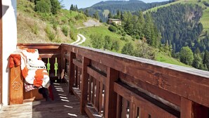 A wooden balcony with a view of a winding road and forested hills. - Apartment Near the ski Resort (Sankt Johann im Pongau)