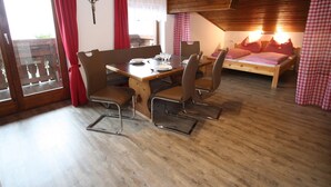 A cozy room with a wooden dining table, chairs, a bed, and a cross on the wall. - Apartment Near the ski Resort (Sankt Johann im Pongau)