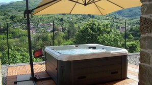 Un jacuzzi en una terraza al aire libre con vista a un pueblo en la ladera.