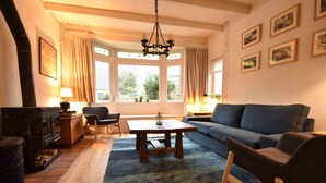 A cozy living room with a fireplace, a sofa, a coffee table, and a chandelier. - Comfortable Holiday Home in Bergen (Bergen)