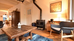 A cozy living room with a wooden table, a blue rug, a chair, a fireplace, and a lamp. - Comfortable Holiday Home in Bergen (Bergen)