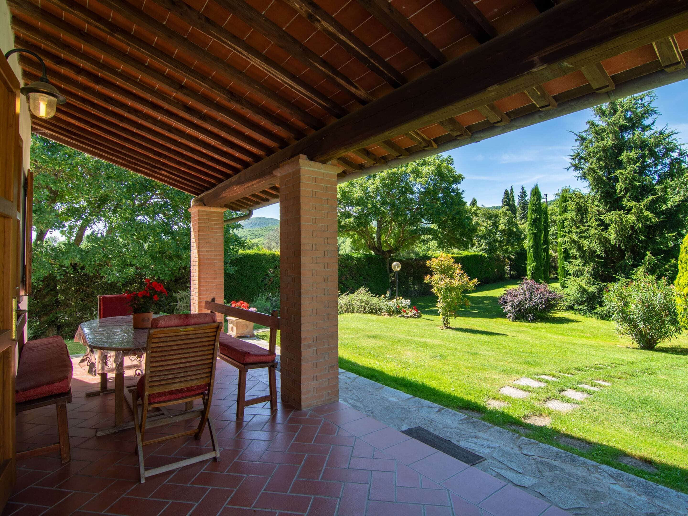Une terrasse extérieure avec un sol en briques, des meubles en bois et une vue sur un jardin bien entretenu.