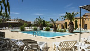 A pool area with lounge chairs, palm trees, and a clear blue sky. - Provencal Parkside Haven (Arles)