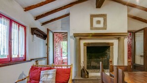 A cozy room with a wicker sofa, a wooden table, and a fireplace. - Vintage Vacation Home (San Marcello Piteglio)