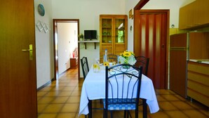 A dining area with a table set for two, a wooden cabinet, and a kitchen area with a refrigerator. - Sunlit Home With Pool (Fucecchio)