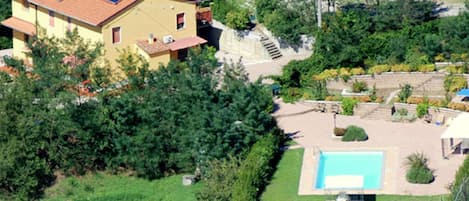 A house with a solar panel roof, a swimming pool, and a garden.