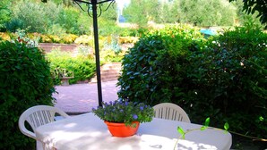 A patio with a table and chairs, surrounded by lush greenery and a brick pathway. - Sunlit Home With Pool (Fucecchio)