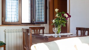 A dining area with a wooden table, chairs, a vase with flowers, and a window with curtains. - 360 Degree View of the Tuscan (Buonconvento)