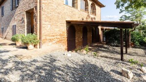 A rustic stone building with a covered patio and gravel ground. - 360 Degree View of the Tuscan (Buonconvento)