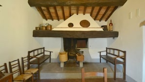 A rustic room with a wooden ceiling, a fireplace with pots and baskets, and wooden benches. - Farmhouse in Mugello With Valley Views (Borgo San Lorenzo)
