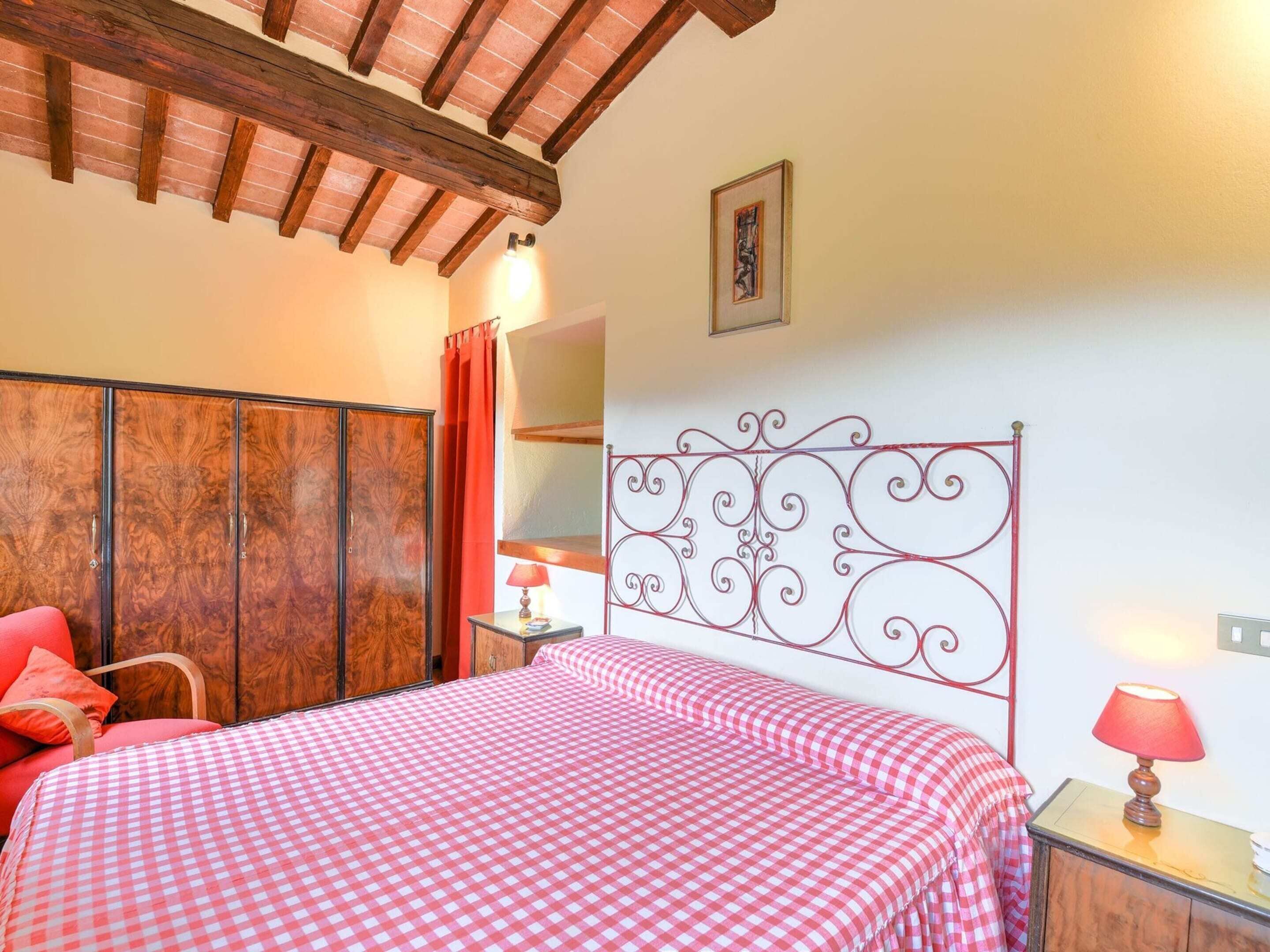A bedroom with a checkered bedspread, wooden wardrobe, and a decorative metal headboard.