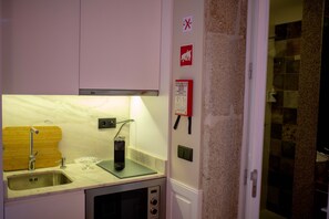 A compact kitchen with a sink, a microwave, and a wooden cutting board.