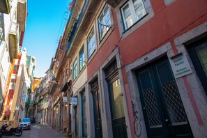 Una calle estrecha flanqueada por edificios, un letrero que dice 'Atelier Escuela Restaurante Antiguidades', y una moto estacionada.