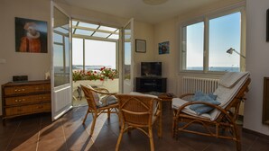 Una habitación con muebles de mimbre, un televisor y vista al mar.