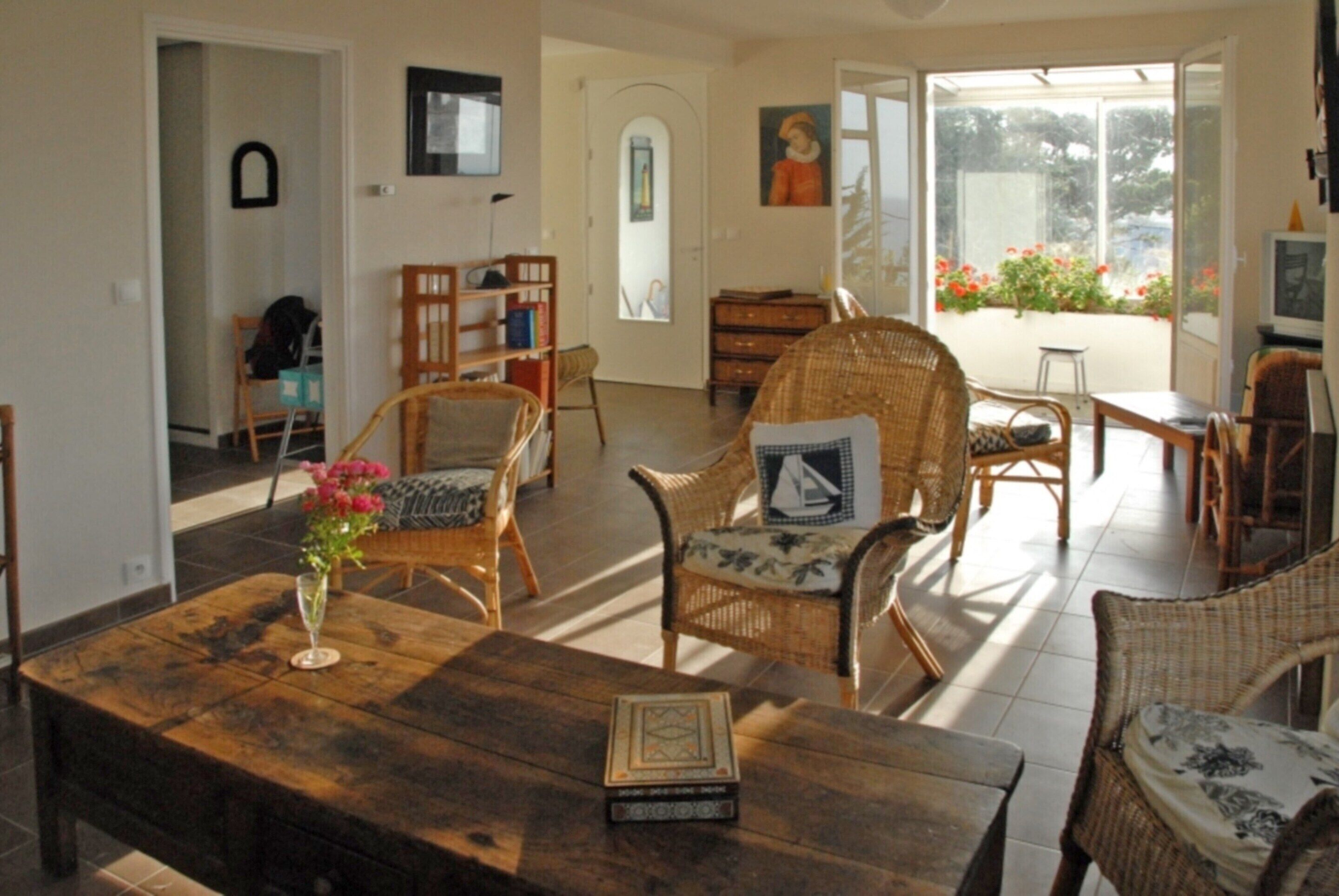 A living room with wicker furniture, a wooden coffee table, and a view through a glass door.