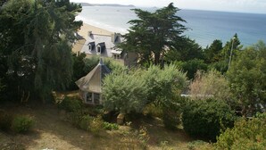 Propiedad costera con vista a la playa, una casa pequeña y abundante vegetación.