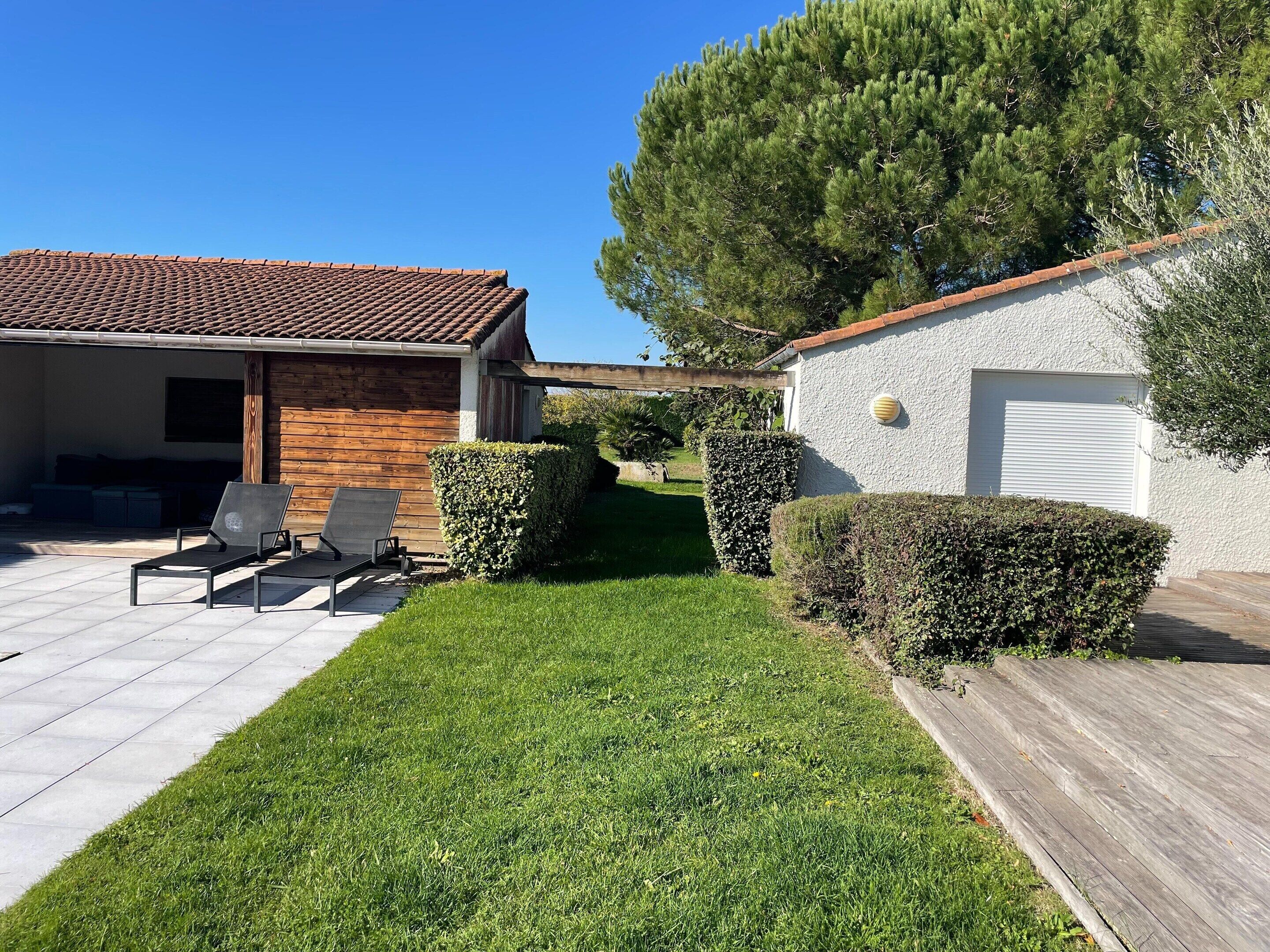 A house with a tiled roof, a wooden deck, and a well-maintained lawn.