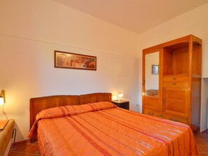 A bedroom with a wooden bed, a nightstand with a lamp, a wardrobe, and a framed picture on the wall. - Peccioli Family Retreat (Peccioli)
