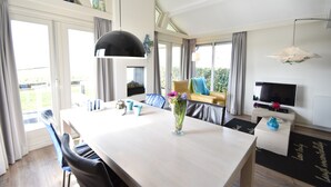 Un salon moderne avec une grande table à manger, un canapé et un téléviseur.
