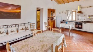 A cozy room with a bed, a dining table, and a kitchen area. - Tuscan Charm Near Volterra (Volterra)
