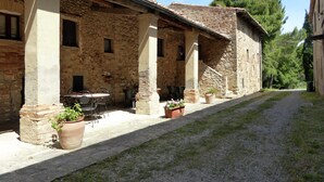 A rustic stone building with a covered patio area, outdoor seating, and potted plants. - Tuscan Charm Near Volterra (Volterra)