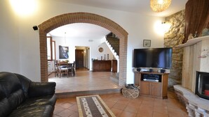 A living room with a leather sofa, a TV, and a fireplace. - Charming Villa in Suvereto with Hot Tub (Suvereto)