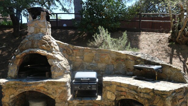 An outdoor stone oven with a grill and a trash can. - Charming Villa in Suvereto with Hot Tub (Suvereto)