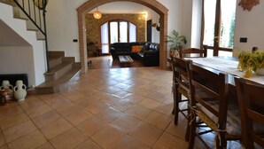 A spacious living area with a stone archway, a black leather sofa, and a dining table with chairs. - Charming Villa in Suvereto with Hot Tub (Suvereto)