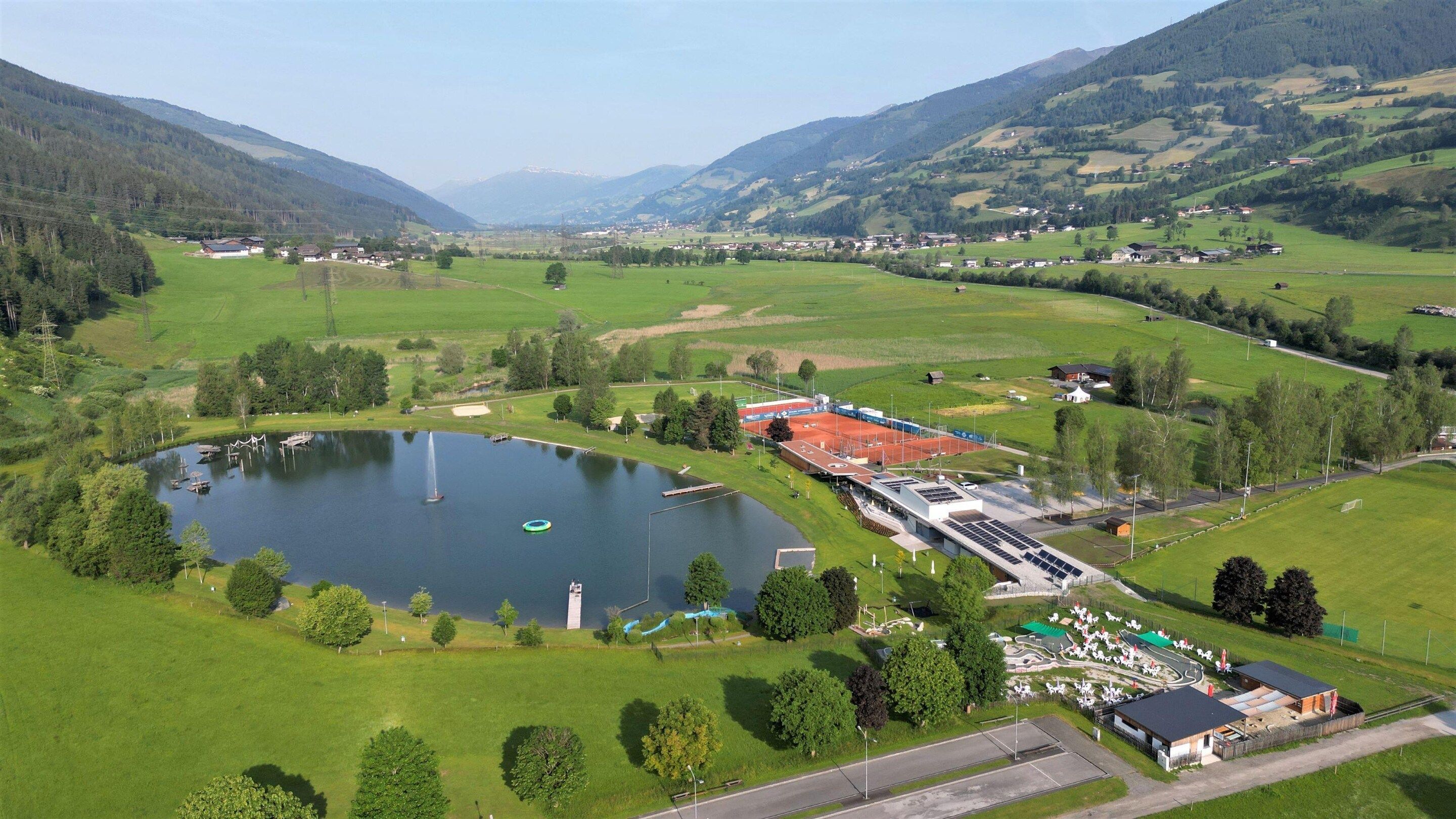 A lakeside facility with a large building, a dock, and a pond.