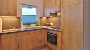 Une cuisine compacte avec des meubles en bois, un four encastré, une fenêtre et un évier.