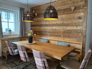 A dining area with a wooden table and benches, pendant lights, and a wall-mounted decoration. - Holiday Home in Niedernsill With Sauna (Niedernsill)