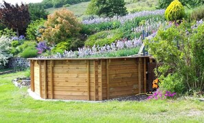 A wooden structure with a roof, surrounded by a garden with various plants and flowers. - Relaxing Retreat in Saint-pons (Saint-Pons)