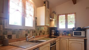 A kitchen with a dishwasher, oven, microwave, and a window with curtains. - Relaxing Retreat in Saint-pons (Saint-Pons)