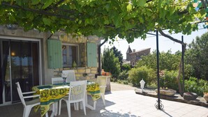 An outdoor patio with a table and chairs, a stone building in the background, and a garden area. - Relaxing Retreat in Saint-pons (Saint-Pons)