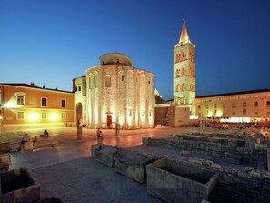 Explore the historic square, featuring a round tower and clock tower, surrounded by beautifully preserved architecture and stone benches.