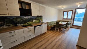 A modern kitchen with wooden cabinets, a built-in stove, and a dining area with a bench and chairs. - Warm Apartment in Uttendorf Salzburg near Ski Area (Uttendorf)