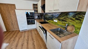 A compact kitchen with wooden cabinets, a built-in oven, microwave, and dishwasher. - Warm Apartment in Uttendorf Salzburg near Ski Area (Uttendorf)