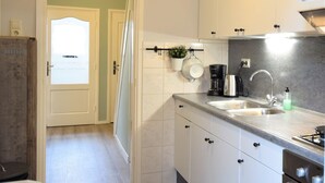 Eine moderne Küche mit weißen Schränken, einer doppelten Spüle, einer Kaffeemaschine und einem Gasherd.