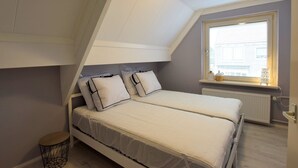 Ein Schlafzimmer mit einem Etagenbett, einem kleinen runden Tisch, einem Fenster mit Jalousien und einer Heizung.