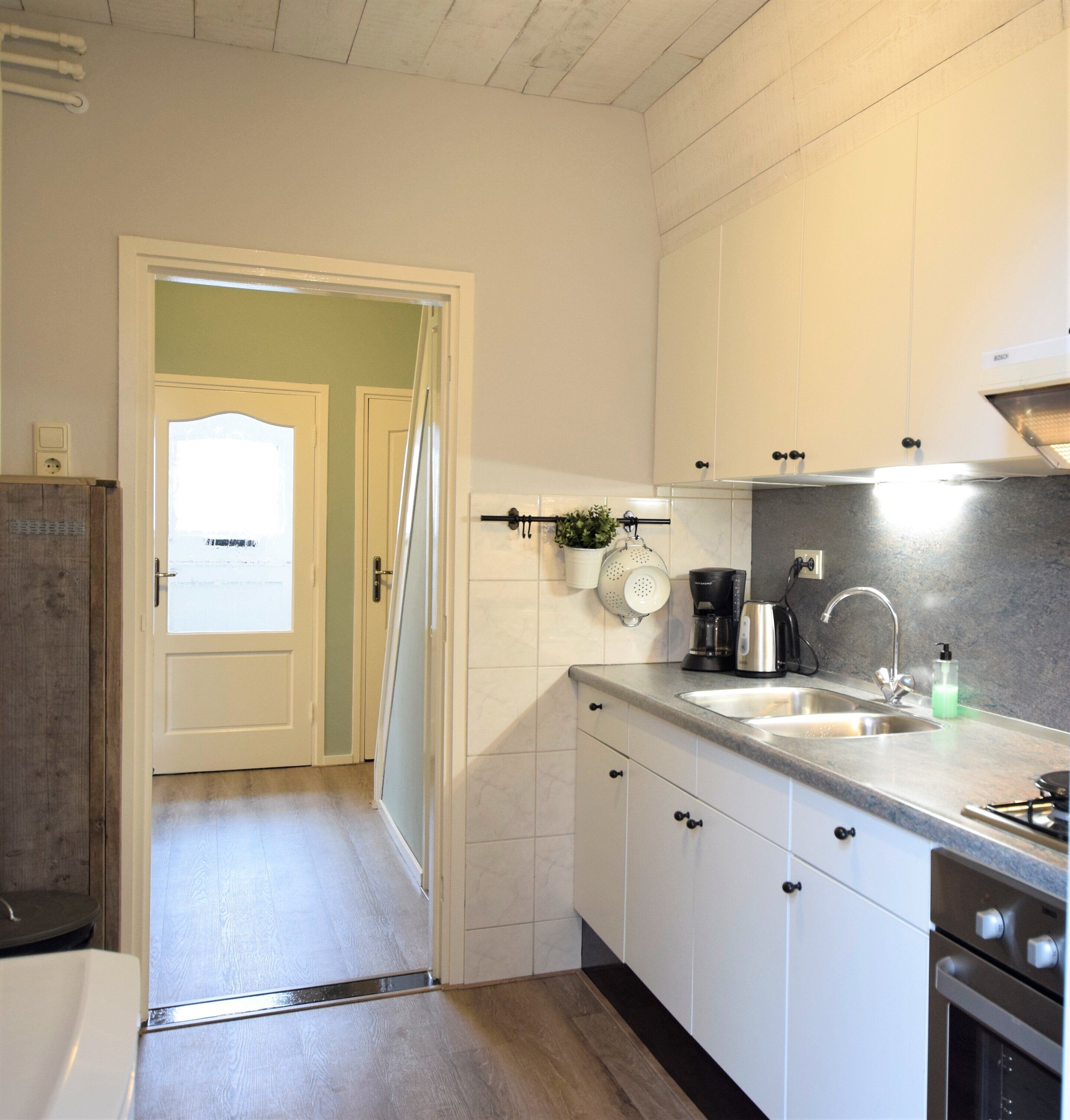 A modern kitchen with white cabinets, a stainless steel sink, and a Bosch coffee maker.