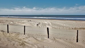 Ein Sandstrand mit Fußspuren und einem Zaun.