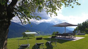 A grassy outdoor area with a table and chairs under a large umbrella, overlooking a mountainous landscape. - Rustic Mansion in Mittersill near Kirchberg Ski Area (Mittersill)
