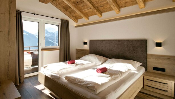 A bedroom with a wooden ceiling, a large bed with white linens, two bedside tables, and a window with a view of mountains. - Rustic Mansion in Mittersill near Kirchberg Ski Area (Mittersill)