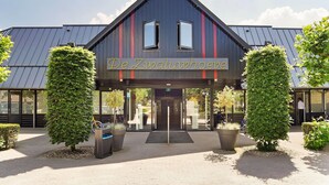 A building with a dark facade and a sign reading "De Zwaluwhoeve". - Finnish Chalet with Private Garden & Sauna near Veluwe (Hulshorst)
