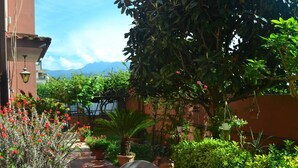 An outdoor dining area with a table set for two, surrounded by potted plants and a view of mountains in the background. - Belvilla by OYO Casa Rosada (Pompei)