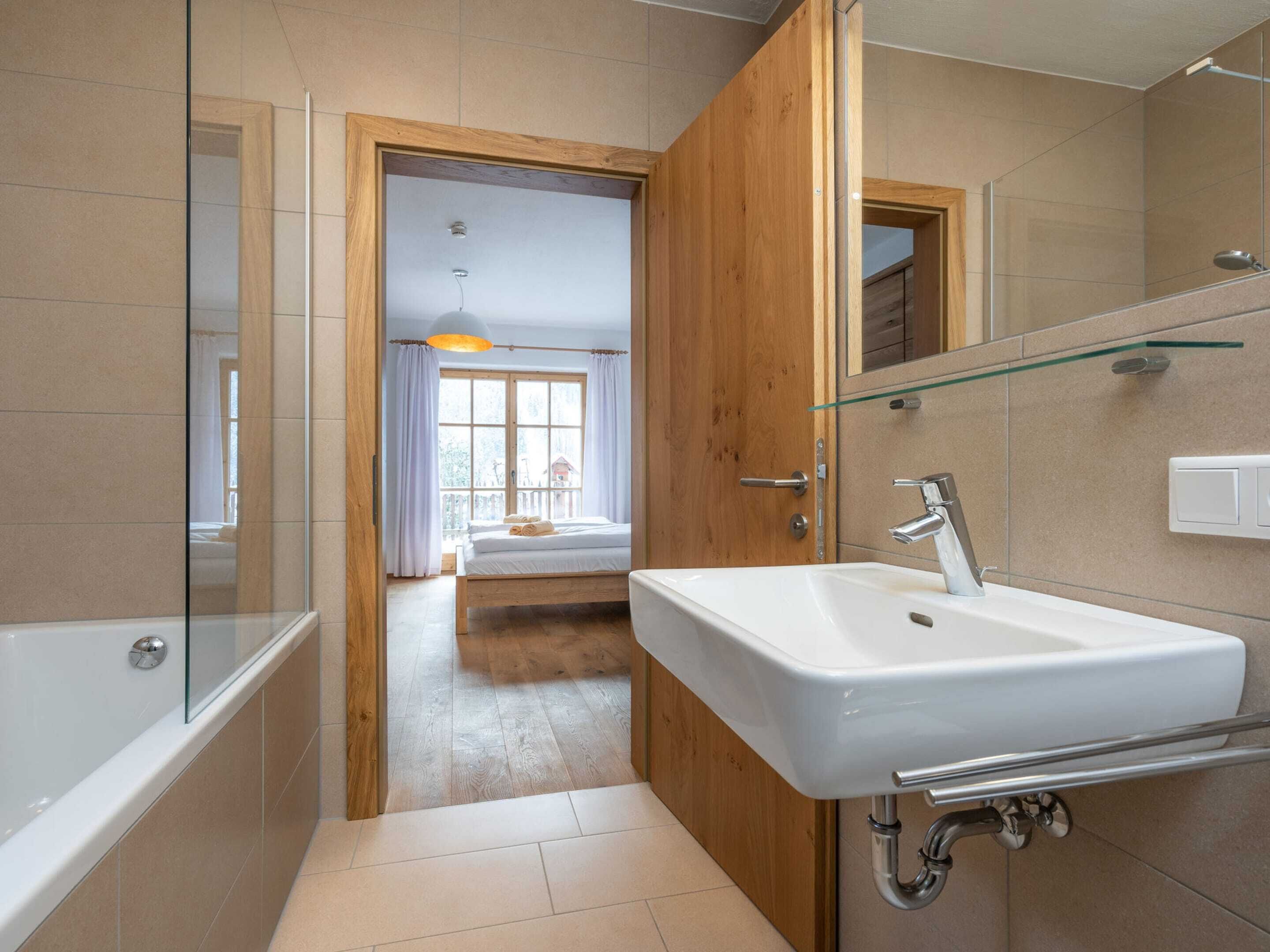 Ein modernes Badezimmer mit einem großen Waschbecken, Spiegel und einer Duschkabine aus Glas.