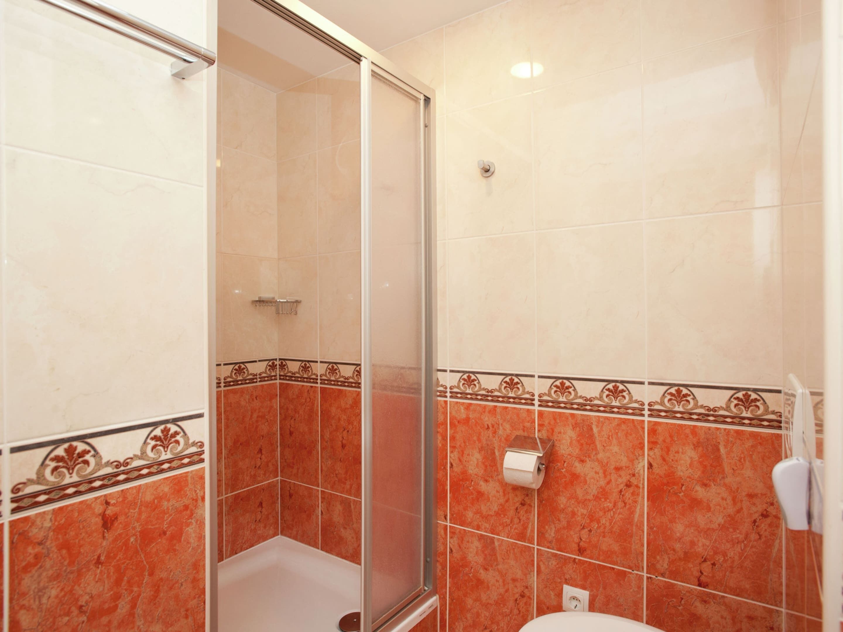 A bathroom with a glass shower enclosure, a toilet, and a towel rack.