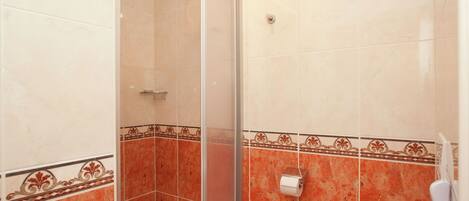 A bathroom with a glass shower enclosure, a toilet, and a towel rack.