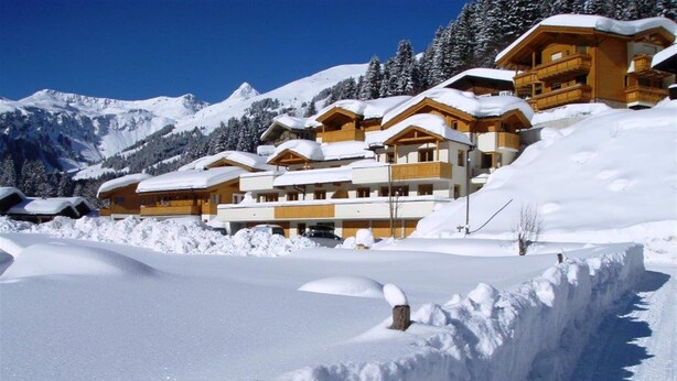 Un resort en la montaña cubierto de nieve, con edificios de madera y cielo despejado.